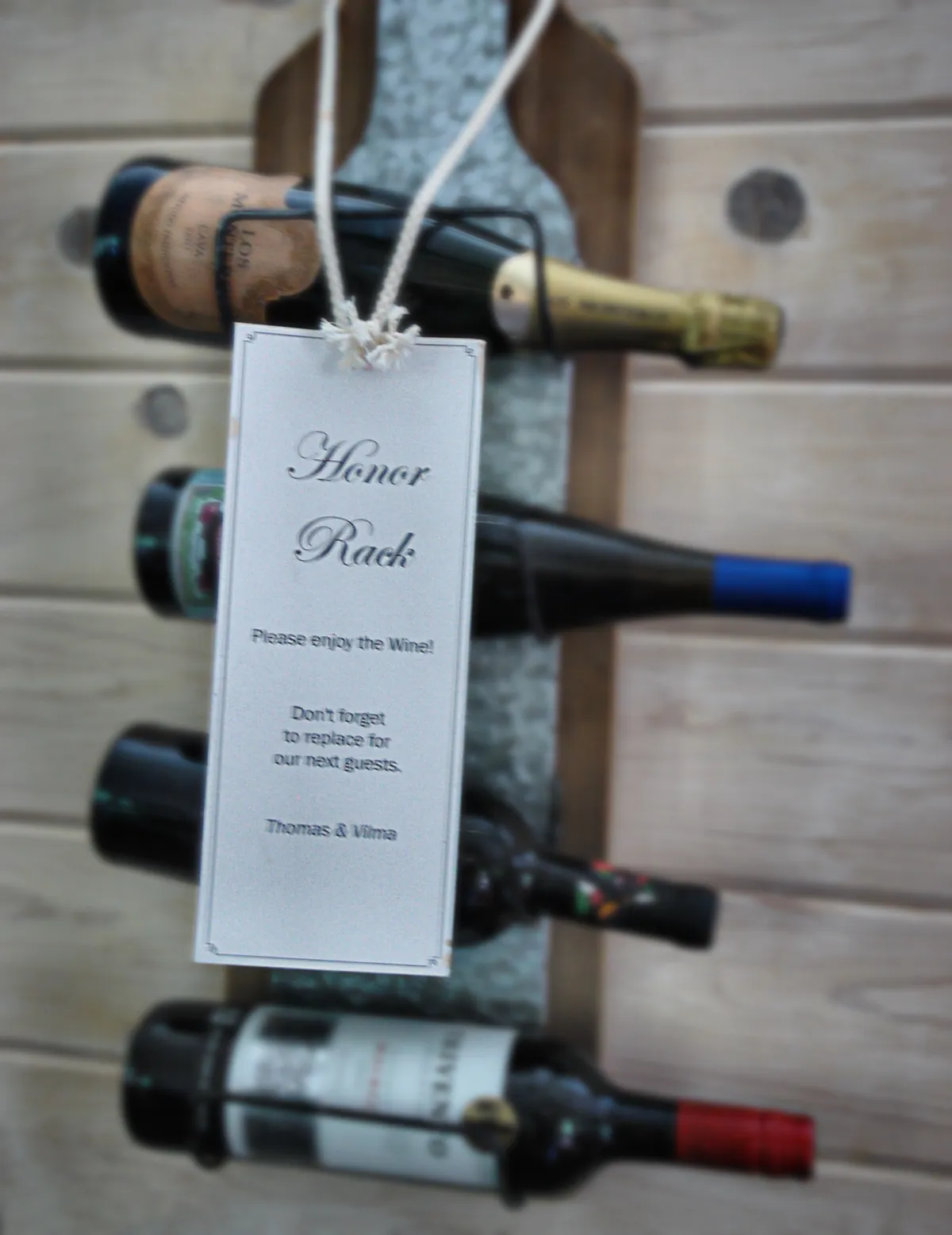 A cozy corner inside the home dedicated to the wine sharing rack, with an 'Honor Rack' sign and an assortment of wine bottles. The mood is social and intimate, encouraging guests to gather and share stories over a glass of wine.
