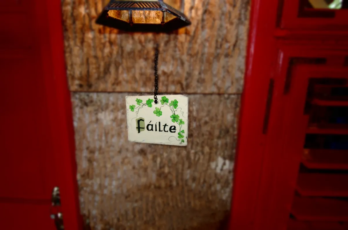 This image captures the home's interior entryway, featuring a warm welcome sign, a vibrant red door, and a textured wall. The scene sets the initial impression for guests and evokes the sense of arrival and hospitality.
